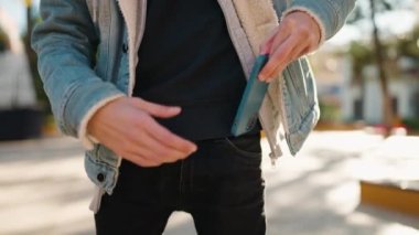 Genç İspanyol adam gülümsüyor. Parktaki akıllı telefondan konuşuyor.