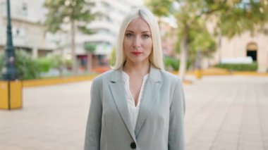 Young blonde woman executive smiling confident standing at park
