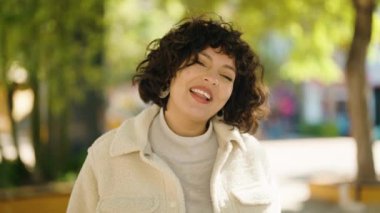 Young hispanic woman smiling confident speaking at park