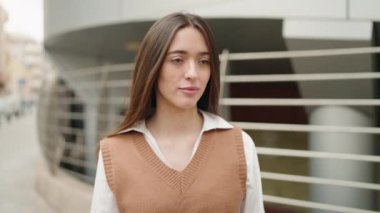 Young hispanic woman standing with relaxed expression at street