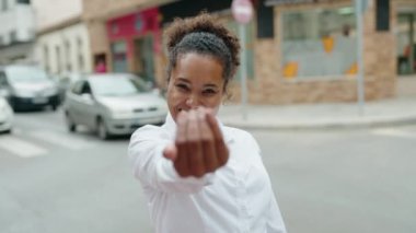 Afro-Amerikalı kadın gülümsüyor kendinden emin bir şekilde sokakta el ele hareket ediyor.