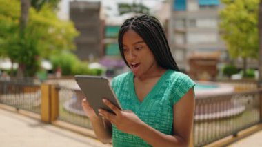 African american woman using touchpad with winner expression at park