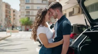 Young hispanic couple smiling confident hugging each other and kissing at street