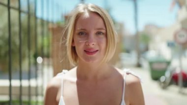 Young blonde woman smiling confident listening to music and dancing at street
