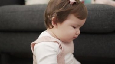 Adorable toddler bitting plastic hoop sitting on floor at home