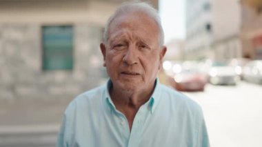 Yaşlı gri saçlı adam caddede dinlemediği için acı çekiyor.