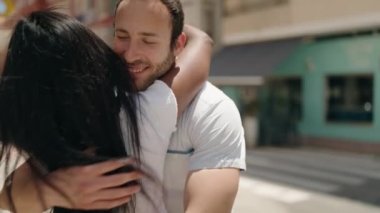 Man and woman interracial couple hugging each other at street