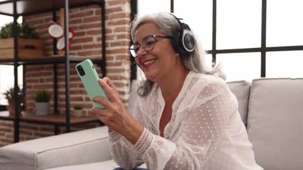Středního Věku Šedovlasá Žena Úsměvem Sebevědomě Pomocí Smartphone Sluchátka Doma — Stock video