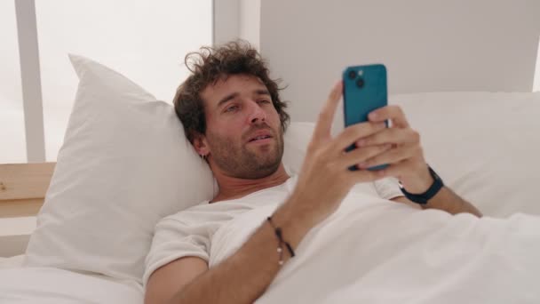 Jonge Spaanse Man Met Behulp Van Smartphone Gapen Slaapkamer — Stockvideo