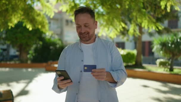 Young Caucasian Man Using Smartphone Credit Card Park — Αρχείο Βίντεο