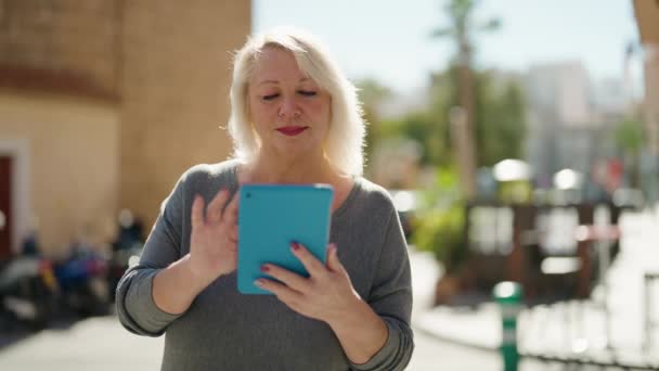 Blonde Frau Mittleren Alters Lächelt Selbstbewusst Mit Touchpad Auf Der — Stockvideo