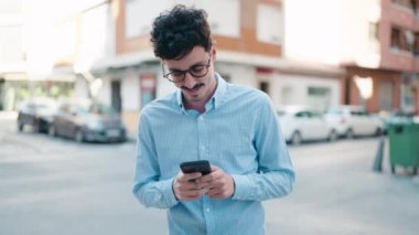 Sokakta akıllı telefon kullanan, kendine güvenen genç bir İspanyol.