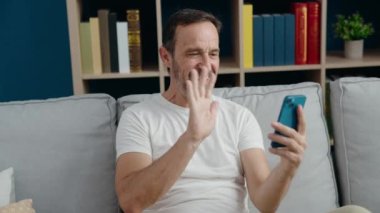 Middle age man having video call sitting on sofa at home