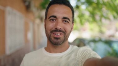 Young hispanic man smiling confident having video call at street