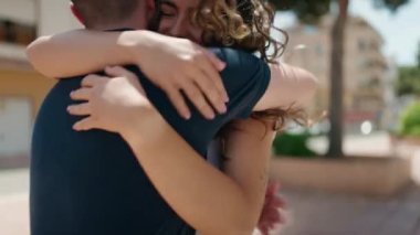 Young hispanic couple smiling confident hugging each other at street
