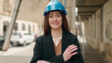Young hispanic woman architect standing with arms crossed gesture at street
