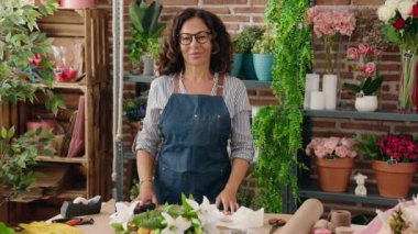 Middle age woman florist smiling confident standing with arms crossed gesture at flower shop