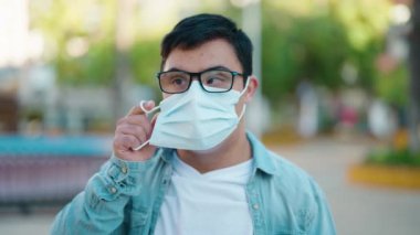 Down syndrome man smiling confident wearing medical mask at park