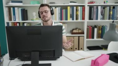 Young caucasian man student using computer taking notes at library university