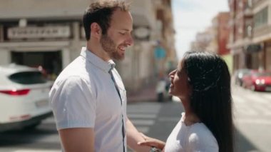 Man and woman interracial couple standing together and kissing at street