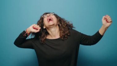 Middle age woman smiling confident dancing over blue background