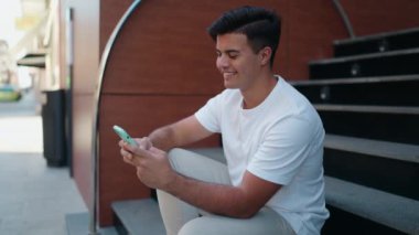 Sokakta akıllı telefon kullanan, kendine güvenen genç bir İspanyol.