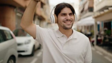 Genç İspanyol adam kendinden emin bir şekilde gülümsüyor. Kahve dükkanının terasında müzik dinliyor ve dans ediyor.