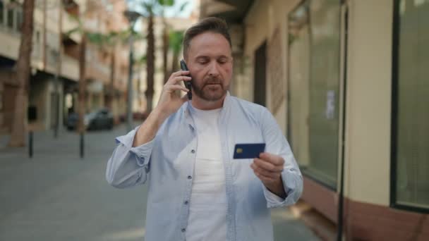 Νεαρός Καυκάσιος Μιλάει Στο Smartphone Κρατώντας Πιστωτική Κάρτα Στο Δρόμο — Αρχείο Βίντεο