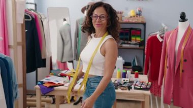 Middle age woman tailor smiling confident standing with arms crossed gesture at clothing factory