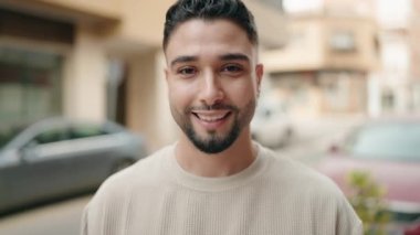 Genç Arap adam sokakta kendine güvenerek gülümsüyor.