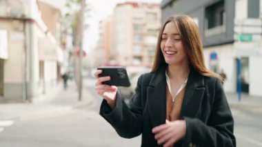 Young hispanic woman smiling confident watching video on smartphone at street