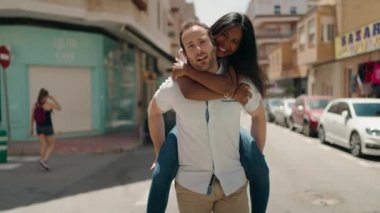 Man and woman interracial couple holding on back walking at street
