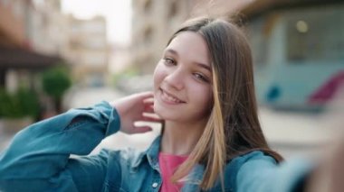 Adorable girl smiling confident making selfie by the camera at street