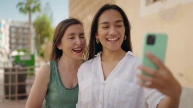 Two women mother and daughter having video call at street