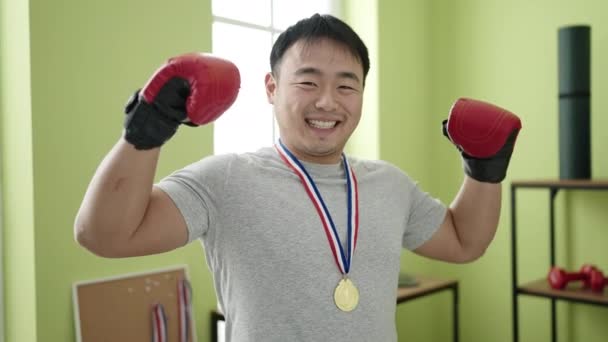 若いです中国人男性行います強いジェスチャー身に着けているメダルでスポーツセンター — ストック動画