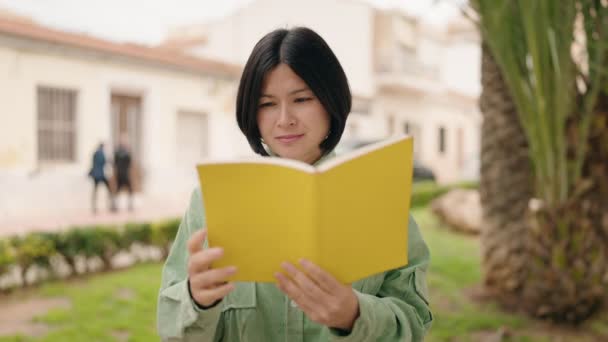 Genç Çinli Kadın Parkta Rahat Bir Ifadeyle Kitap Okuyor — Stok video