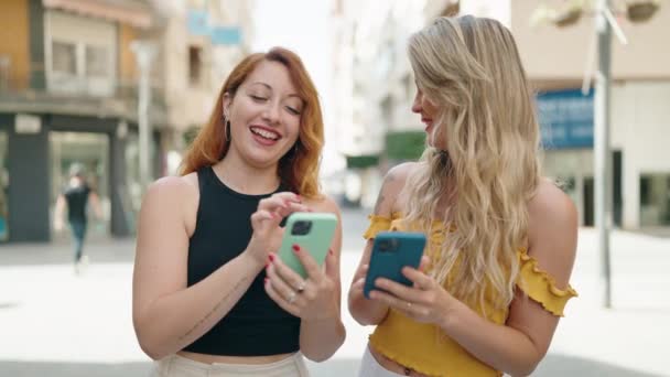 Δύο Γυναίκες Που Στέκονται Μαζί Χρησιμοποιώντας Smartphones Στο Δρόμο — Αρχείο Βίντεο
