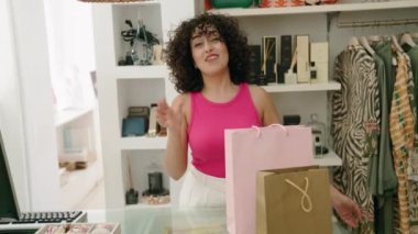 Young middle eastern woman shop assistant smiling confident speaking at clothing store