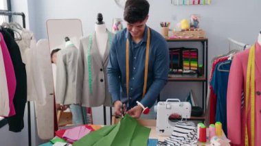 Genç İspanyol terzi gülümsüyor. Kıyafet fabrikasında kumaş kesiyor.