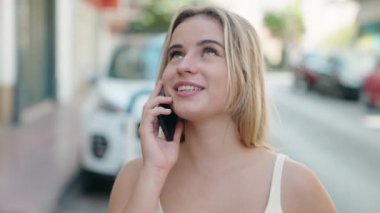 Genç sarışın kadın gülümsüyor. Kendine güveni tam. Akıllı telefondan konuşuyor.