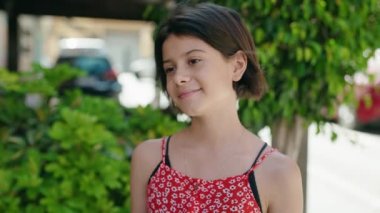 Adorable hispanic girl smiling confident looking to the side at street