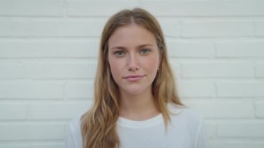 Young blonde girl smiling confident pointing with finger to credit card over isolated white brick background