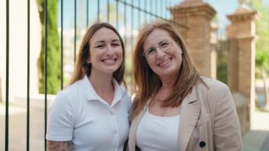 Anne ve kızı gülümsüyor, sokakta birbirlerine sarılıyorlar.