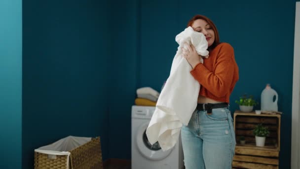 Young Redhead Woman Smiling Confident Smelling Soft Clothes Laundry Room — Videoclip de stoc