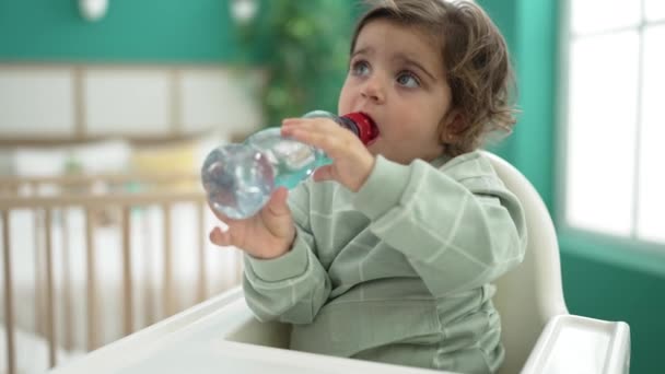 Adorable Hispanic Girl Sitting Baby Highchair Drinking Water Bedroom — Stockvideo