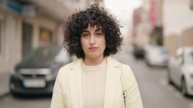 Sokakta ciddi bir ifadeyle duran genç bir kadın.