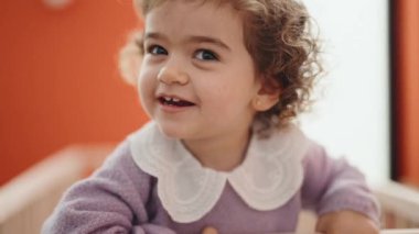 Adorable hispanic girl smiling confident standing on cradle at bedroom