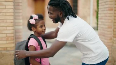 Father and daughter standing together speaking at school