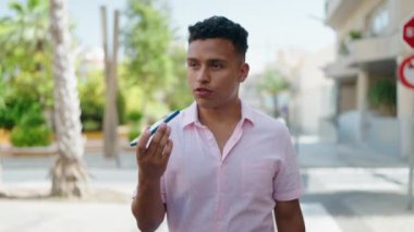 Young latin man smiling confident talking on the smartphone walking at street