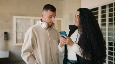 Young couple smiling confident using smartphone at street